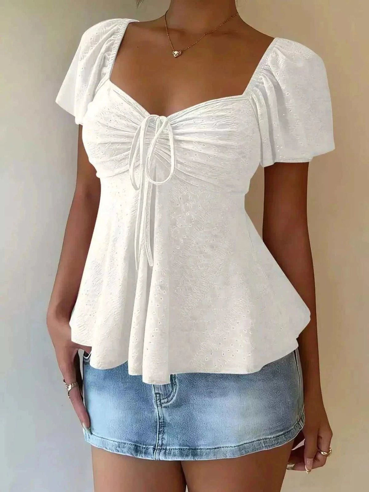 Sweetheart Neck white polyester eyelet top with ruched bust, tie-front detail, puff sleeves, and peplum hem